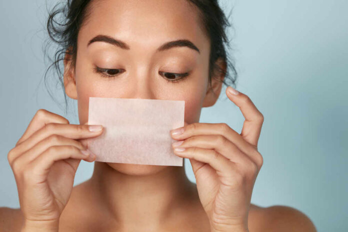 Woman holding a skincare strip in front of her face
