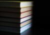 Shocking Book List Rewires Minds A stack of books with colorful spines against a dark background