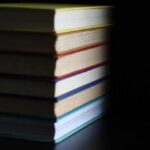 A stack of books with colorful spines against a dark background