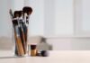 The Shocking Reality of Makeup Brush Filth A collection of makeup brushes in a glass container on a table