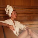 Woman relaxing in a sauna wearing a robe and towel