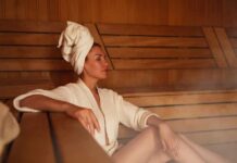 Cardio Boost: Sauna Sessions Without the Sweat Woman relaxing in a sauna wearing a robe and towel
