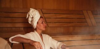 Woman relaxing in a sauna wearing a robe and towel