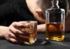 Black Urine WARNING: Is Your Liver Failing? A person with their head down, holding a glass of whiskey next to a bottle