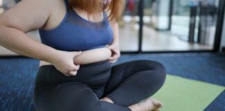 Person sitting on a yoga mat adjusting their clothing