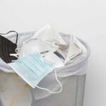 A trash bin filled with various discarded face masks