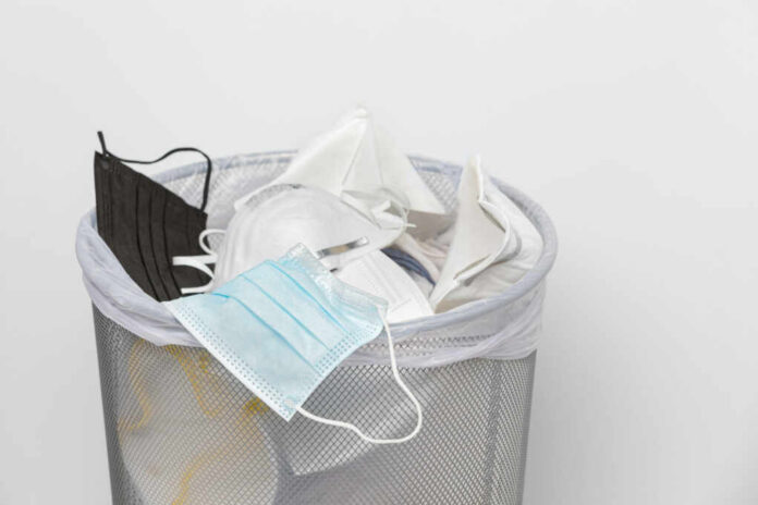 A trash bin filled with various discarded face masks