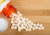 GERD Meds: Heartburn Relief or Health Hazard? Spilled white pills from a prescription bottle on a wooden surface