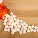 Spilled white pills from a prescription bottle on a wooden surface