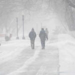 People walking in a snowy park during a blizzard