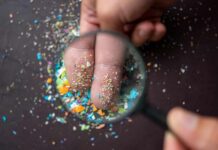 Hand Photo Test Spots Deadly Disease A hand holding a magnifying glass over fingers covered in colorful particles