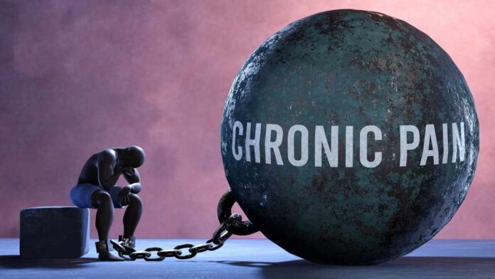 A figure representing chronic pain, sitting beside a large ball labeled 'CHRONIC PAIN' chained to their body