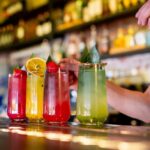 A bartender preparing colorful cocktails at a bar
