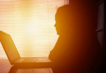 The Power of Introverts in Modern Workplaces Silhouette of a person working on a laptop with sunlight streaming through blinds