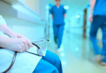 Hidden Costs of Doctor Burnout Revealed A healthcare professional holding a stethoscope in a hospital corridor