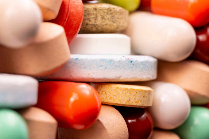 A close-up view of a variety of colorful pills and tablets stacked together