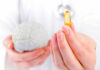 A medical professional holding a brain model in one hand and a yellow supplement capsule in the other