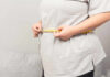 Estrogen’s Secret Role in Weight Loss Revealed Person measuring their waist with a tape measure