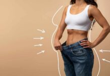 Woman showcasing weight loss by holding oversized jeans