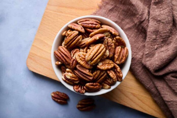 Bowl of pecans on a wooden cutting board