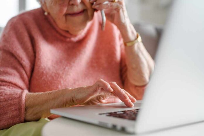 shutterstock_2466940953.jpg Elderly woman on a phone call while using a laptop