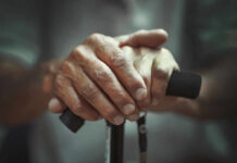 How to Maintain Muscle Mass While Aging Close-up of elderly hands resting on a walking cane