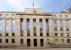 Facade of a government building with the words Law and Justice and a statue on top
