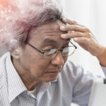 Elderly man looking stressed while using a digital device