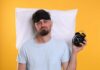 Gut Sabotage: Why You Can’t Sleep Man wearing a sleep mask holding an alarm clock with a frustrated expression