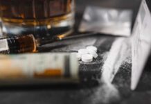 Meth and HIV: A Dangerous Link Uncovered A close-up of a syringe, pills, and a glass of alcohol on a dark surface