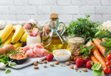 A variety of fresh foods including fruits, vegetables, and oils arranged on a table