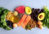 Food Foundations That Help Both Gut and Hormone Health An assortment of healthy foods including fish, nuts, fruits, and vegetables arranged on a light background
