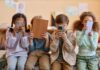 What Excessive Screen Time Does to your Brain and Body Four children sitting together, each engaged with their electronic devices