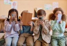 What Excessive Screen Time Does to your Brain and Body Four children sitting together, each engaged with their electronic devices