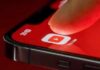 Finger tapping YouTube app icon on smartphone screen