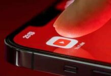 Finger tapping YouTube app icon on smartphone screen