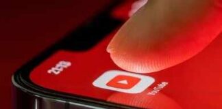 Finger tapping YouTube app icon on smartphone screen