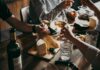 Hands toasting wine glasses over a cheese board