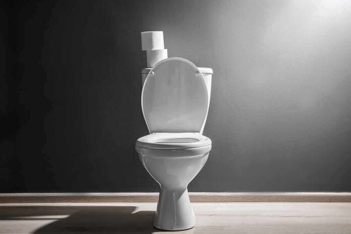 shutterstock_1114196873 White toilet with open lid against gray wall