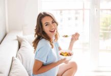 How to Create a Personalized Wellness Plan That Actually Sticks Woman sitting on a couch eating a bowl of fruit salad