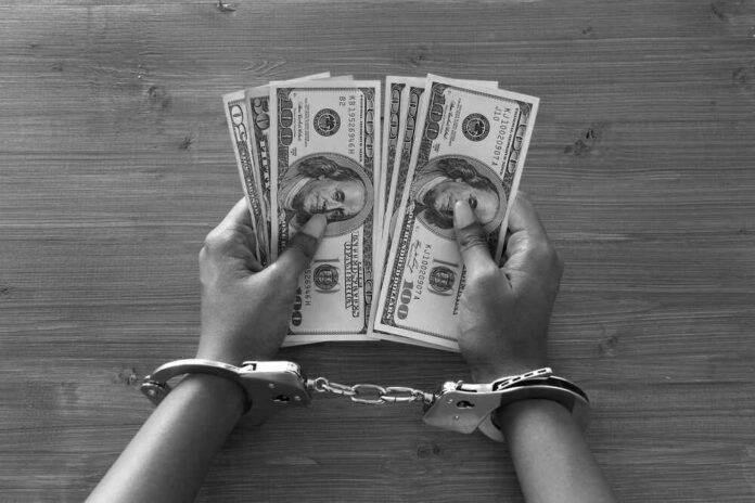 Prisoner,With,Handcuffs,Holding,Dollar,Bills Hands in handcuffs holding stacks of cash