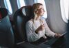 Passenger with headphones seated by airplane window