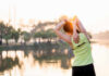 Hidden Culprit Behind Back Aches A woman stretching her arms by a lake during sunrise