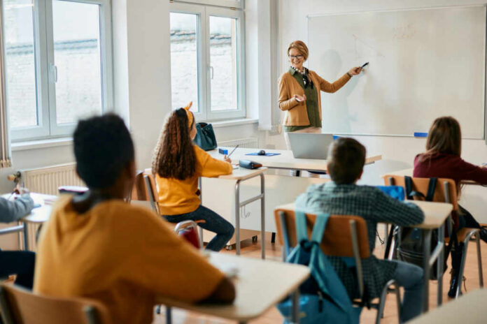 shutterstock_2109193706-1 Teacher explaining a math concept to students in a classroom