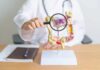 Doctor examining an anatomical model of the digestive system with a magnifying glass
