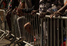Close-up of hands resting on a barrier in a crowded urban setting