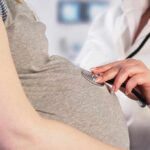 Pregnant woman examined with stethoscope