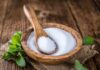 5 foods you’re eating everyday that are more HARMFUL than sugar Wooden bowl of white granules with spoon and green leaves