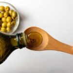 Pouring olive oil from a bottle into a wooden spoon