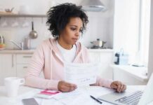 Effects Of A Higher Pay On Stress Woman reviewing bills at a kitchen table with a laptop